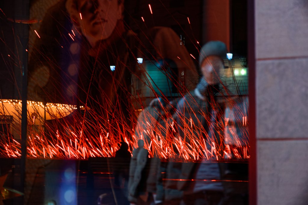 Les illuminations de la place de la République se reflétant dans une vitrine.